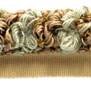 May include: A close-up of a beige trim with a ruffled edge. The trim is made of a soft, textured fabric and has a subtle sheen. The trim is perfect for adding a touch of elegance to any project.