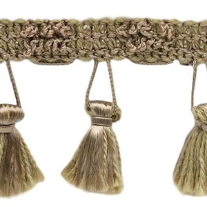 May include: A beige tassel trim with a woven design and fringe. The trim has a series of tassels that hang down from the woven band.