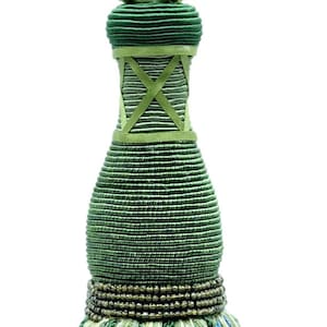 Op de afbeelding: Groene en blauwe kwast met een kralenrand en een groene touwband. De kwast heeft een lange, slanke vorm en is versierd met kleine pompoenen.