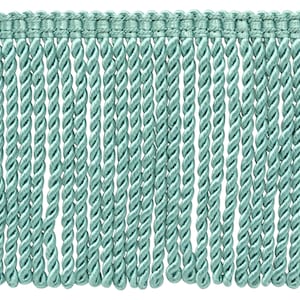 May include: A close-up of a light blue twisted fringe trim. The fringe is made of a soft, silky material and has a subtle sheen.