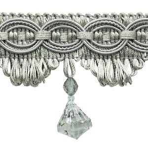 May include: Silver trim with a beaded fringe and crystal-like drops. The trim has a woven design with a repeating oval pattern.