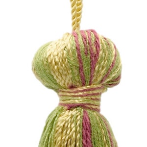 May include: A green, pink, and yellow tassel with a long, yellow cord. The tassel is made of yarn and has a fringed bottom.