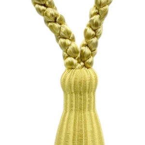 Può includere: Un fiocco dorato con un cordoncino intrecciato e una perla decorativa. Il fiocco è fatto di un materiale morbido e soffice e ha una lunga frangia fluida.