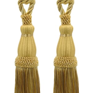 Può includere: Due fermatenda a nappina dorati con un design a corda. Le nappine sono realizzate in un tessuto morbido e intrecciato e hanno una frangia sul fondo.