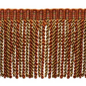 May include: A close-up of a twisted cord fringe trim in shades of orange and gold. The fringe is made of multiple strands of twisted cord, creating a textured and decorative look.