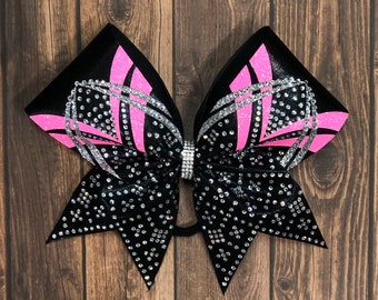 May include: A black and pink cheer bow with silver accents and rhinestones. The bow is tied in a classic cheer bow shape.