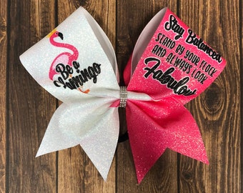 May include: White and pink cheer bow with glitter. One side features a pink flamingo with the text "Be a Flamingo". The other side features the text "Stay Balanced, Stand by your flock and always look Fabulous".