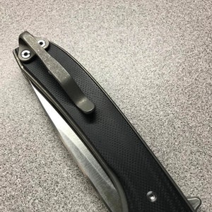 May include: A black pocket knife with a silver clip and a textured black handle.