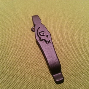 Puede incluir: Un llavero de metal negro con un diseño de calavera.