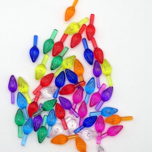 Peut inclure: Une collection d'ampoules de Noël colorées dans différentes nuances de rouge, orange, jaune, vert, bleu, violet et transparent. Les ampoules ont la forme de larmes et sont dotées d'une petite pointe métallique.