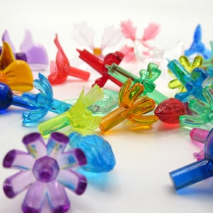 Op de afbeelding: Assortiment van kleurrijke plastic kerstlampjesafdekkingen. De afdekkingen hebben verschillende vormen, waaronder bloemen, vogels en sterren.