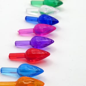 Puede incluir: Surtido de puntas de bombillas de luces navideñas de colores en varios colores, incluyendo amarillo, verde, transparente, azul, rosa, morado, rojo, azul claro y naranja.
