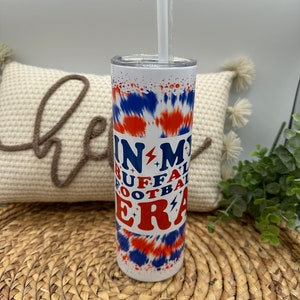 May include: White stainless steel tumbler with a blue and orange tie-dye pattern. The tumbler has the text "In My Buffalo Football Era" printed on it.