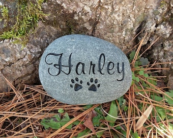 May include: A gray stone with the name "Harley" engraved in cursive lettering and two paw prints.