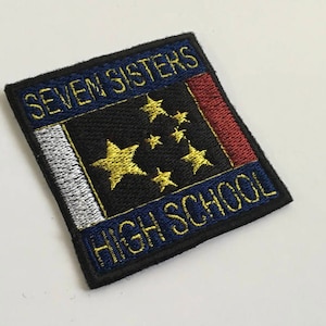 May include: A blue and black embroidered patch with the text "Seven Sisters High School" and a white and red flag with gold stars.