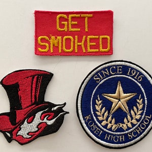Puede incluir: Tres parches bordados. Un parche rojo con texto amarillo que dice "GET SMOKED". Un parche negro y rojo con un sombrero de copa rojo y llamas. Un parche azul y blanco con una estrella dorada y el texto "SINCE 1916 KOSEI HIGH SCHOOL".