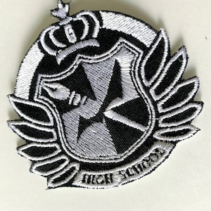 May include: Black and white embroidered patch with a crown, wings, and a shield with a cross inside. The text "Hope's Peak Academy" is written on the bottom of the patch.