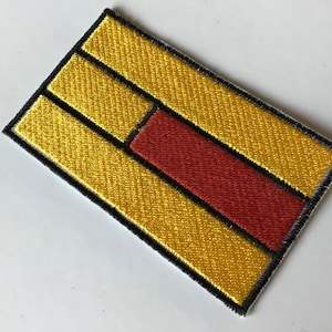 May include: A yellow and red embroidered patch with a black outline. The patch has three horizontal yellow stripes with a red stripe in the middle.