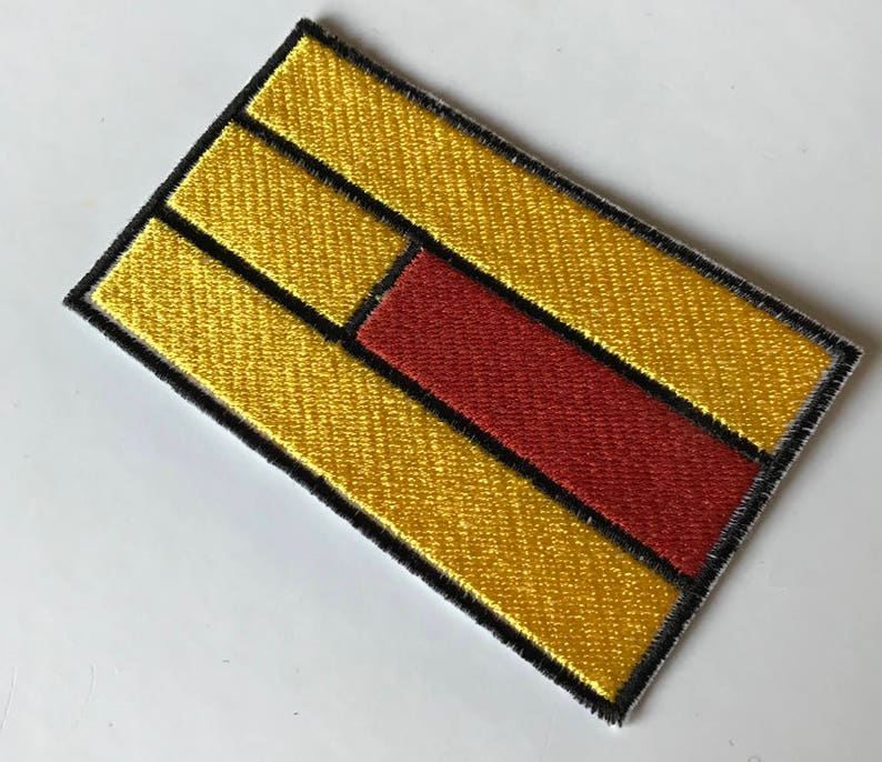 May include: A yellow and red embroidered patch with a black outline. The patch has three horizontal yellow stripes with a red stripe in the middle.