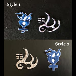 May include: Embroidered patches in two styles. Style 1 features a blue and white design and a white and gray design. Style 2 shows a white and gray design and a blue and white design. The patches are on a black background, with the text "Style 1" and "Style 2".
