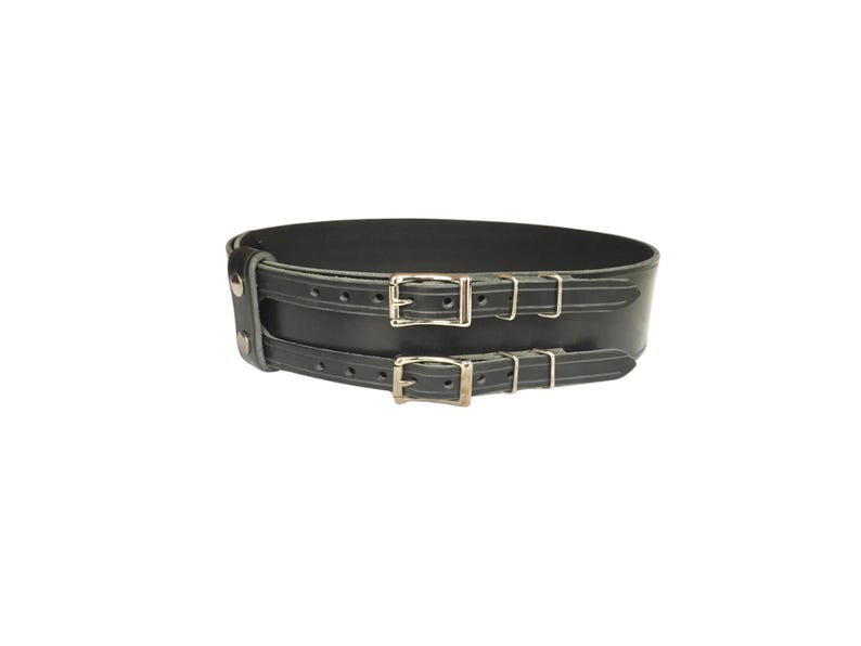 May include: A black leather belt with two silver buckles. The belt is wide and has a smooth finish.