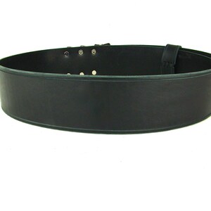 View of back side of black double buckle kilt belt. View features the detail design groove carved along edge of belt strap.