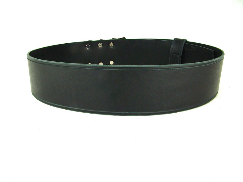 View of back side of black double buckle kilt belt. View features the detail design groove carved along edge of belt strap.