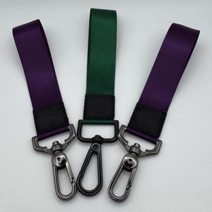 Può includere: Tre portachiavi con clip in metallo. Un portachiavi è viola, uno è verde e uno è viola scuro.