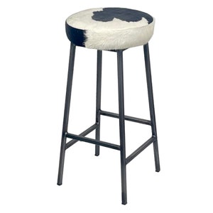May include: A black metal bar stool with a round, white and black cowhide seat.