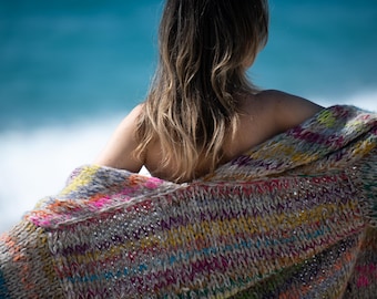 May include: A chunky knit cardigan featuring a multi-colored yarn blend with vibrant streaks of neon pink, yellow, blue, and orange woven into a neutral grey base. The garment has a loose, open-front silhouette with a thick, textured stitch pattern.