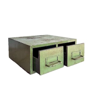 May include: A vintage, olive green metal storage cabinet with two open drawers. The cabinet has a rectangular shape with visible wear and tear, giving it a rustic appearance. Each drawer features a metal handle. The cabinet is suitable for small item storage.