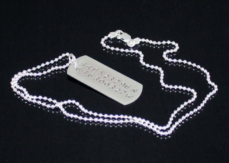 May include: A silver necklace with a silver dog tag pendant. The dog tag has the coordinates 44.652196 N 63.6300327 W engraved on it.