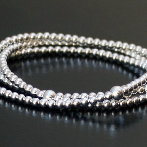 May include: A silver beaded bracelet with three strands of small, round beads.