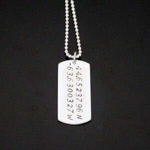May include: Silver necklace with a dog tag pendant engraved with the coordinates 44.6523796 N -63.6300327 W.