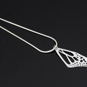 May include: A silver chain necklace with a delicate butterfly pendant. The pendant is made of silver and has a cutout design.