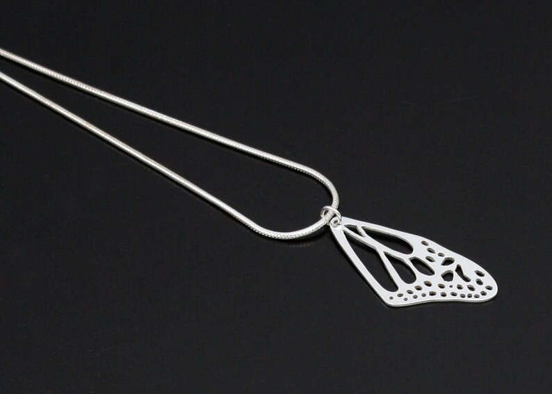 May include: A silver chain necklace with a delicate butterfly pendant. The pendant is made of silver and has a cutout design.
