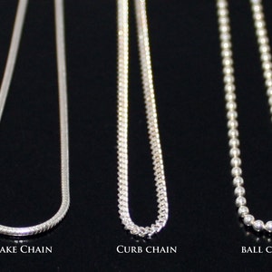May include: Three silver chains, a snake chain, a curb chain, and a ball chain, are displayed against a black background. The chains are all the same length and are hanging straight down.