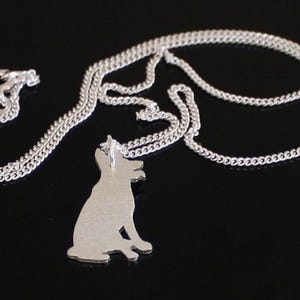 May include: A silver chain necklace with a silver pendant shaped like a dog sitting. The pendant is detailed and has a smooth finish.