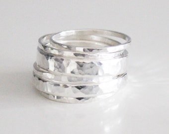 May include: A set of five silver hammered stacking rings. The rings are all different sizes and are stacked on top of each other.
