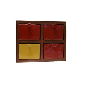 May include: A wooden box with four small ceramic drawers. Two drawers are red and two are yellow.