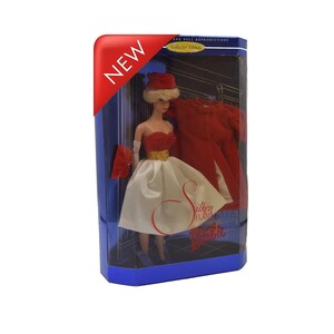 May include: A boxed Barbie doll, a collector's edition, features a red and white dress, matching hat, gloves, and a red coat. The box has a red "NEW" banner and the text "Silken Flame Barbie".
