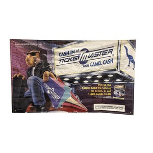 May include: A banner featuring a cartoon camel wearing sunglasses and a leather jacket, holding a Ticketmaster ticket. The banner promotes "Cash in at Ticketmaster with Camel Cash" and includes the phone number 1-800-CAMEL-CASH.