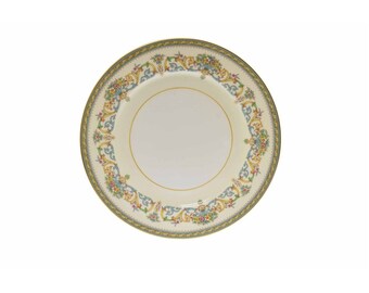 May include: A white ceramic dinner plate with a gold and green border and a floral design in shades of blue, yellow, and pink.
