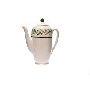 May include: White ceramic coffee pot with a green and brown leaf design around the middle. The pot has a green knob on the lid.