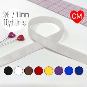 May include: White satin ribbon, 3/8 inch wide, sold in 10 yard units. The ribbon is shown on a white surface with two red hearts and a ruler. The ribbon is available in black, white, brown, red, yellow, purple, blue, and navy.