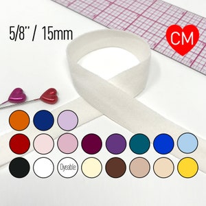 May include: White 5/8 inch (15mm) wide elastic fold over elastic, also known as FOE, in a variety of colors. The elastic is shown folded in half and is available in a variety of colors, including black, white, red, orange, pink, purple, blue, teal, and yellow. The elastic is also available in a dye-able color.