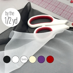 Könnte beinhalten: Weißer und schwarzer transparenter Stoff, verkauft pro halber Yard. Der Stoff ist über einer Schere gefaltet abgebildet. Der Stoff ist in Weiß, Schwarz, Färbbar, Elfenbein, Lila und Rot erhältlich.