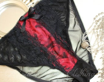May include: Black lace and mesh underwear with a red floral print. The underwear has a bow on the front and a sheer mesh panel on the back.