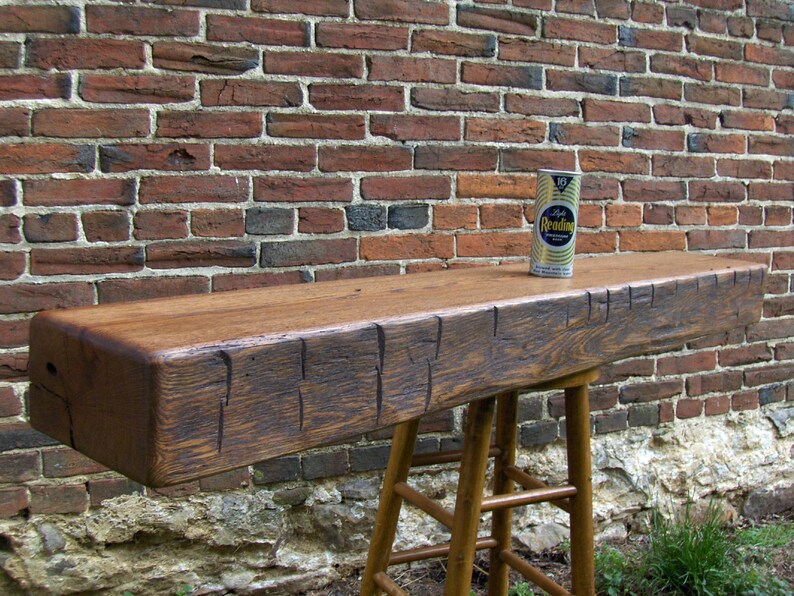 Puede incluir: Un estante de viga de madera r&uacute;stica con un acabado marr&oacute;n desgastado. El estante est&aacute; montado en un taburete de madera con un acabado marr&oacute;n. Una lata vintage de soda "Reading" est&aacute; sentada en el estante.
