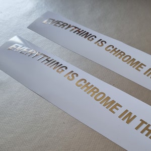 May include: Two white stickers with gold lettering that reads "Everything is chrome in the future".